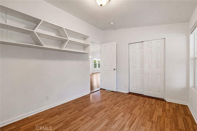 unfurnished bedroom with a closet, baseboards, wood finished floors, and vaulted ceiling