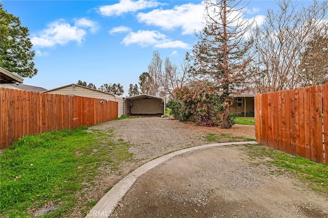 view of yard with gravel driveway, fence, and a detached carport