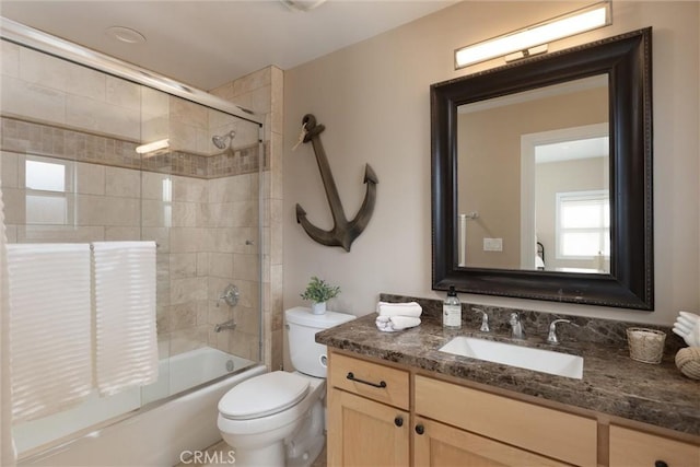 bathroom with combined bath / shower with glass door, toilet, and vanity