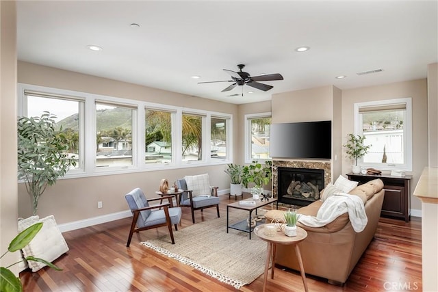 living area featuring visible vents, baseboards, hardwood / wood-style floors, recessed lighting, and a glass covered fireplace