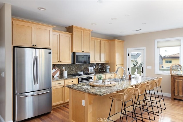 kitchen featuring visible vents, a sink, light brown cabinetry, appliances with stainless steel finishes, and backsplash