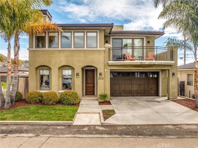 view of front of property featuring stucco siding, a balcony, an attached garage, and driveway