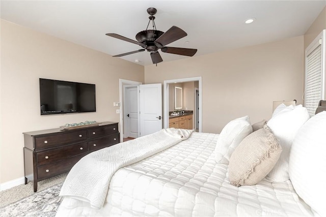bedroom featuring baseboards, ensuite bath, recessed lighting, ceiling fan, and light colored carpet