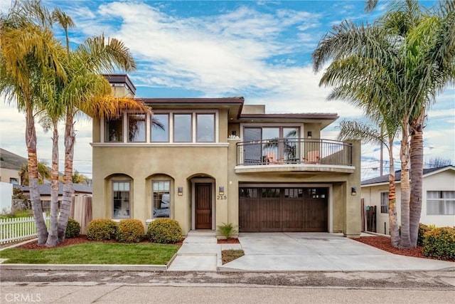 view of front of house with a balcony, fence, an attached garage, stucco siding, and concrete driveway