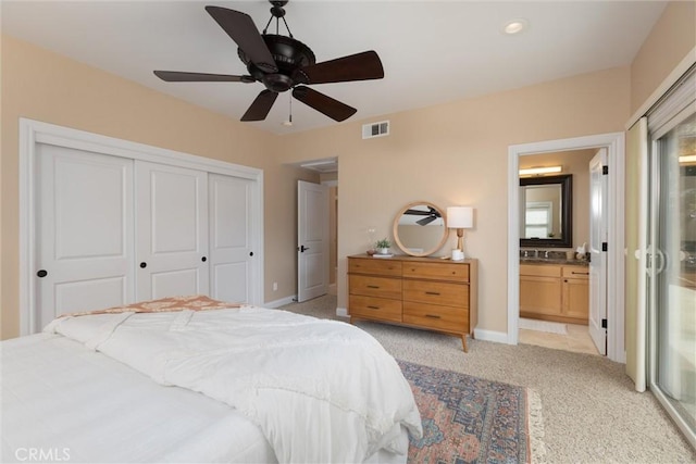 bedroom with visible vents, a closet, connected bathroom, baseboards, and light colored carpet