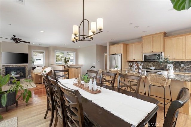 dining area with a glass covered fireplace, recessed lighting, ceiling fan with notable chandelier, and light wood-type flooring