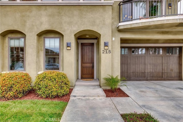 property entrance featuring concrete driveway, a balcony, and stucco siding