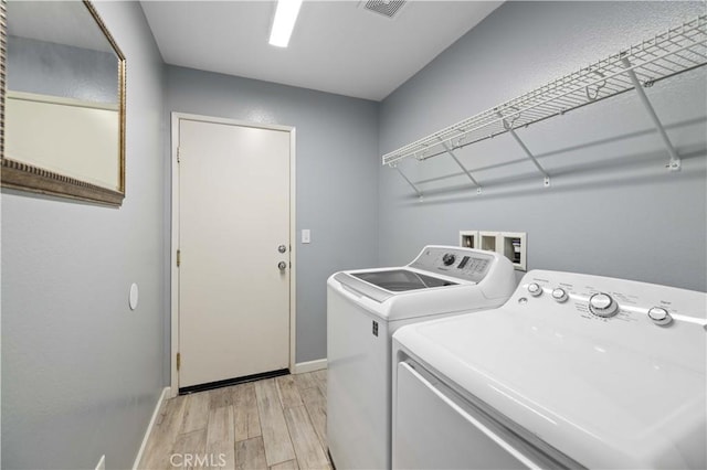 laundry room featuring laundry area, light wood finished floors, baseboards, visible vents, and washing machine and clothes dryer