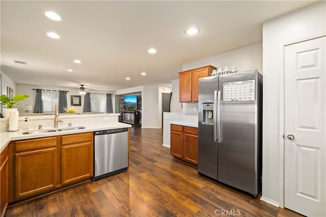 kitchen featuring brown cabinets, dark wood-type flooring, stainless steel appliances, and a sink