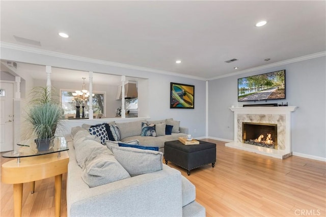 living area featuring baseboards, recessed lighting, a fireplace, crown molding, and light wood-type flooring