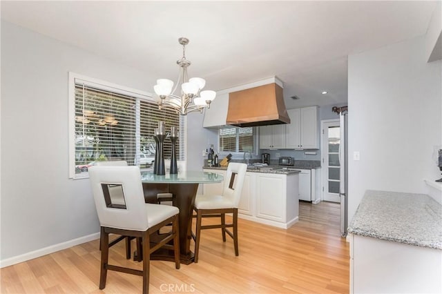 dining space featuring light wood finished floors, a chandelier, and a wealth of natural light