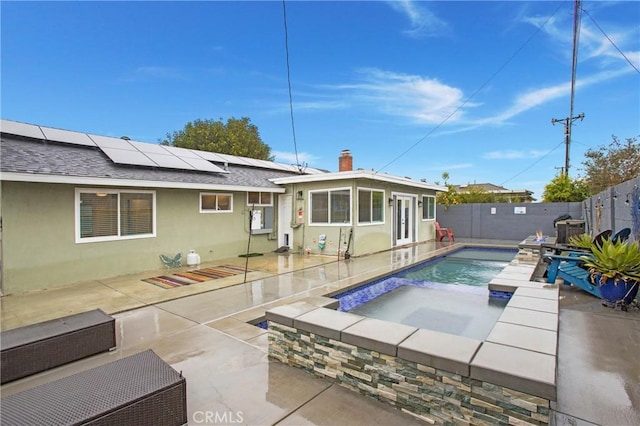 back of property featuring a patio, a fenced backyard, a shingled roof, stucco siding, and roof mounted solar panels