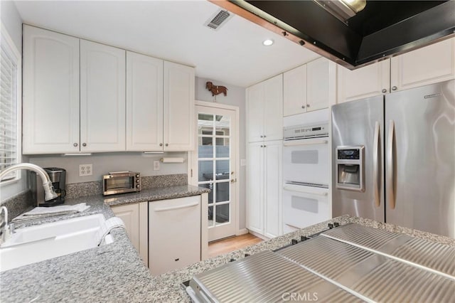 kitchen featuring visible vents, a sink, recessed lighting, white appliances, and white cabinets