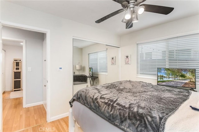 bedroom with a closet, a ceiling fan, light wood-type flooring, and baseboards