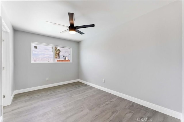 spare room featuring a ceiling fan, baseboards, and wood finished floors