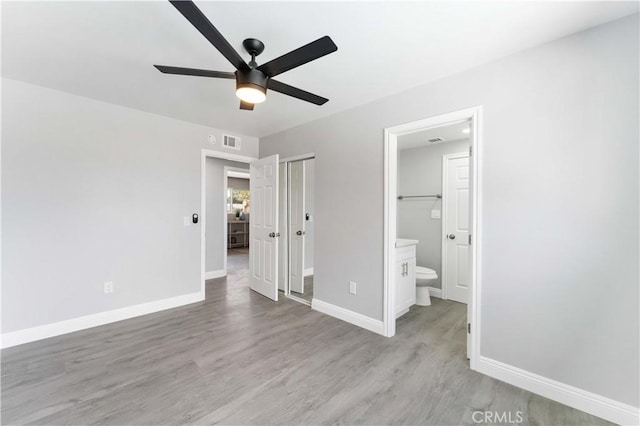 unfurnished bedroom featuring visible vents, light wood finished floors, baseboards, and ensuite bathroom