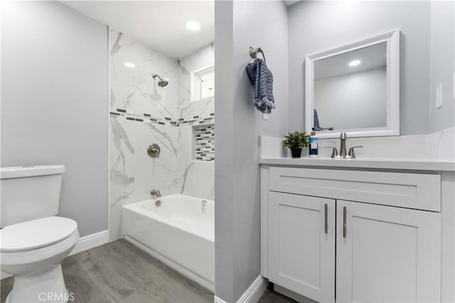 full bath featuring baseboards, bathing tub / shower combination, toilet, wood finished floors, and vanity