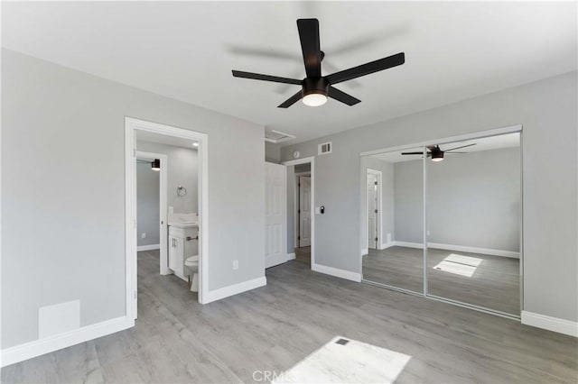 unfurnished bedroom with a closet, wood finished floors, visible vents, and baseboards