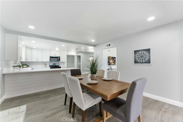 dining space with light wood finished floors, recessed lighting, visible vents, and baseboards