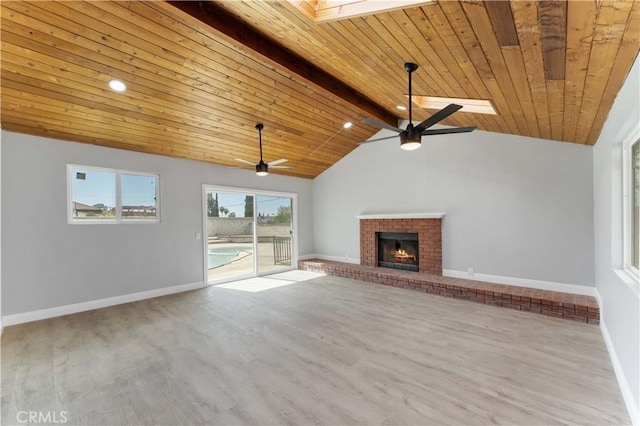 unfurnished living room with a fireplace, lofted ceiling with skylight, wood finished floors, wooden ceiling, and baseboards