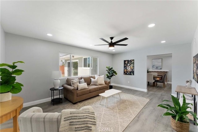 living area featuring light wood-style flooring, a fireplace, baseboards, and recessed lighting