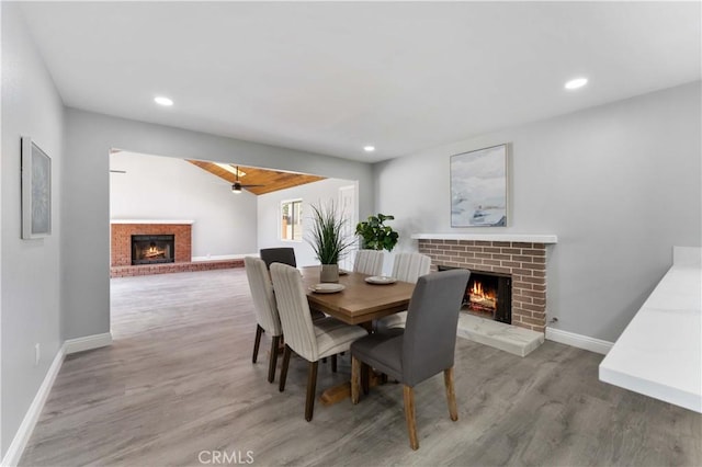 dining space with recessed lighting, a brick fireplace, baseboards, and wood finished floors