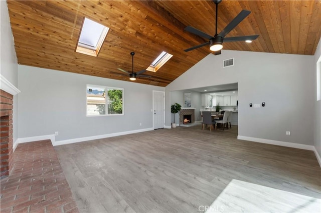 unfurnished living room with a skylight, baseboards, wooden ceiling, a fireplace, and high vaulted ceiling