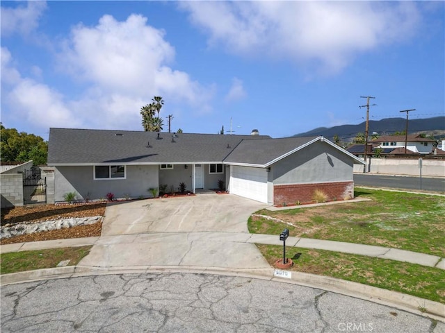 ranch-style house with concrete driveway, brick siding, an attached garage, and stucco siding