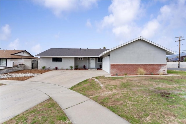 ranch-style house featuring brick siding, driveway, fence, and stucco siding