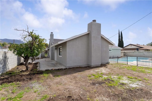 rear view of house featuring a patio area, fence, a fenced in pool, and stucco siding