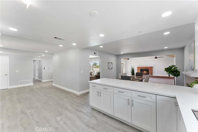 kitchen featuring recessed lighting, a peninsula, a fireplace, visible vents, and open floor plan