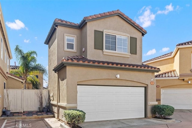 mediterranean / spanish-style house featuring a garage, fence, and stucco siding