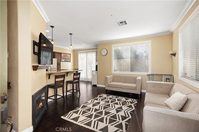 living area with dark wood-style floors, plenty of natural light, visible vents, and crown molding