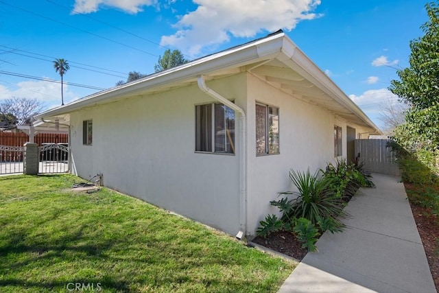 view of home's exterior featuring a lawn, fence, and stucco siding