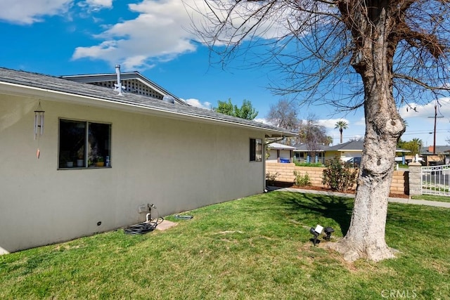 view of side of property featuring fence, a lawn, and stucco siding