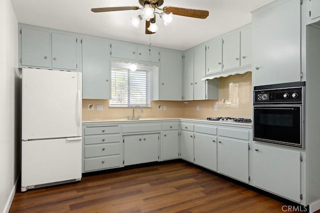 kitchen featuring dark wood-type flooring, white appliances, light countertops, and a sink