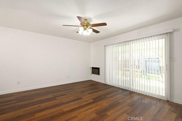 unfurnished living room with dark wood-style floors, baseboards, heating unit, and a ceiling fan