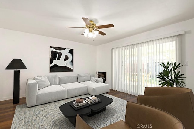 living room featuring ceiling fan, baseboards, and dark wood-type flooring