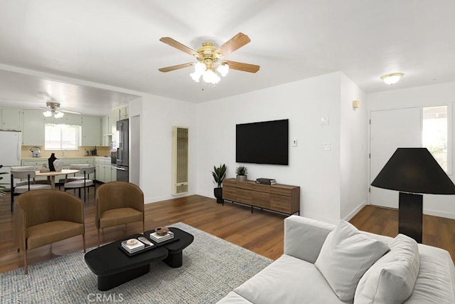 living area featuring dark wood finished floors, a ceiling fan, and baseboards