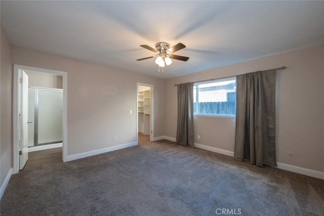 unfurnished bedroom with a spacious closet, carpet, a ceiling fan, and baseboards