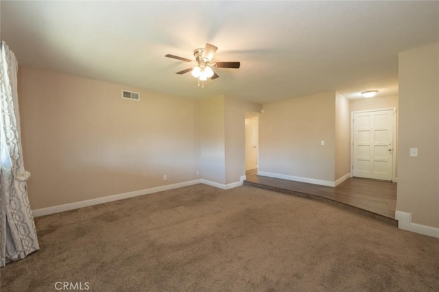 carpeted spare room featuring visible vents, ceiling fan, and baseboards