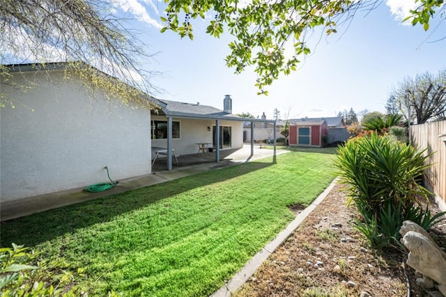 view of yard featuring a patio area, a fenced backyard, an outdoor structure, and a shed