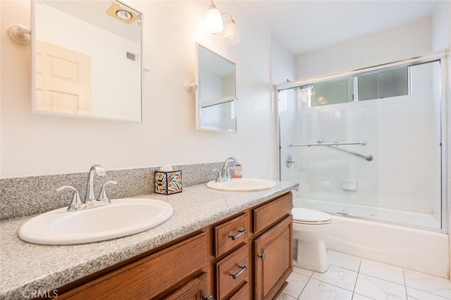 bathroom featuring marble finish floor, double vanity, a sink, and toilet