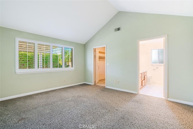 unfurnished bedroom featuring light colored carpet, visible vents, a spacious closet, ensuite bath, and baseboards