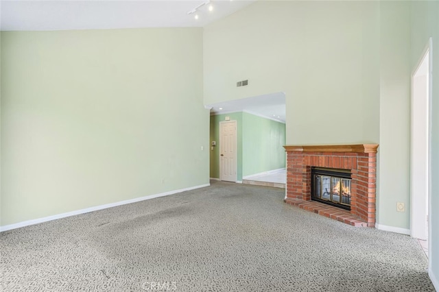 unfurnished living room with track lighting, a high ceiling, a fireplace, and baseboards