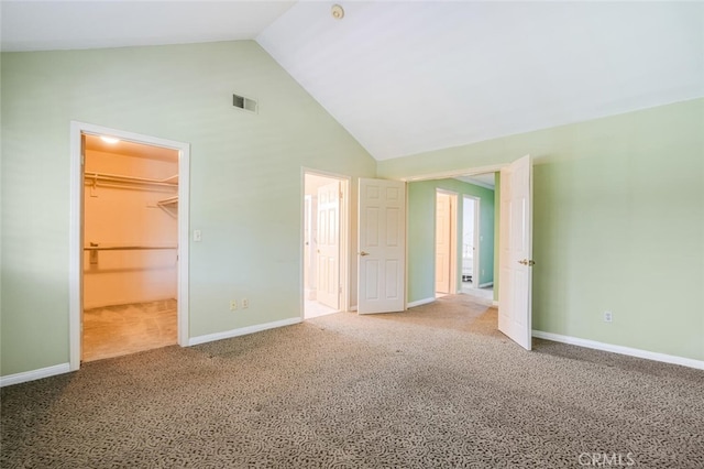 unfurnished bedroom with carpet floors, a walk in closet, visible vents, and baseboards