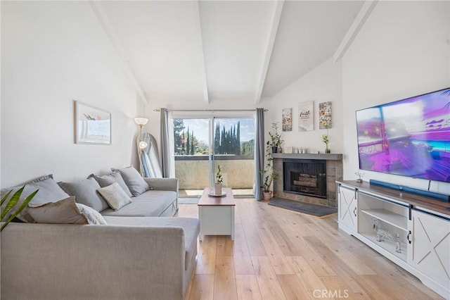 living room featuring vaulted ceiling with beams, light wood finished floors, and a fireplace with flush hearth