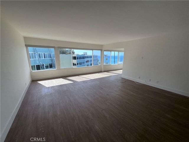 unfurnished room with baseboards and dark wood finished floors