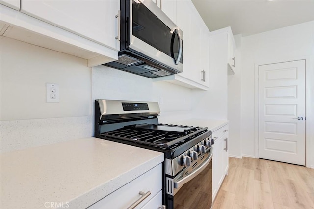 12990 Campbell Ct, Hesperia, CA 92344 - kitchen featuring light wood-type flooring, appliances with stainless steel finishes, white cabinets, and light stone counters