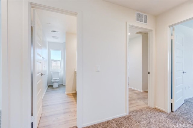 12990 Campbell Ct, Hesperia, CA 92344 - hallway featuring light wood-style floors, visible vents, light carpet, and baseboards